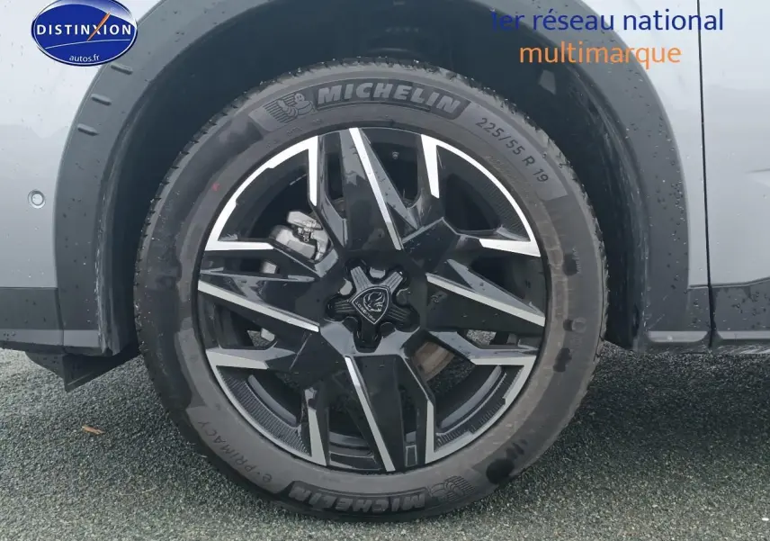 Gros plan sur la roue avant gauche du Peugeot 5008 gris Artense avec jante alliage noire et détails argentés.