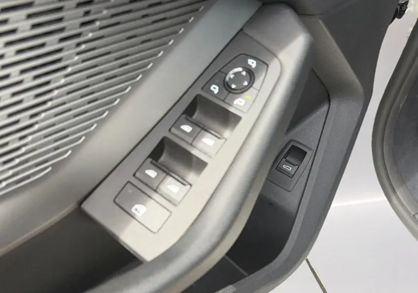 Gros plan sur les commandes des vitres et rétroviseurs côté conducteur d'une BMW Série 1 blanche.
