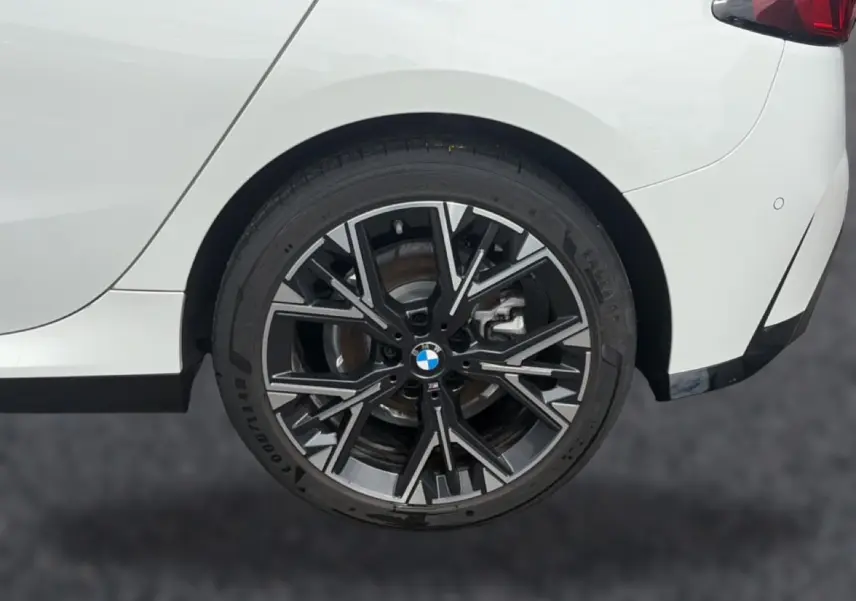 Gros plan sur la roue arrière droite avec jante alliage noire et argentée d’une BMW Série 1 blanche.