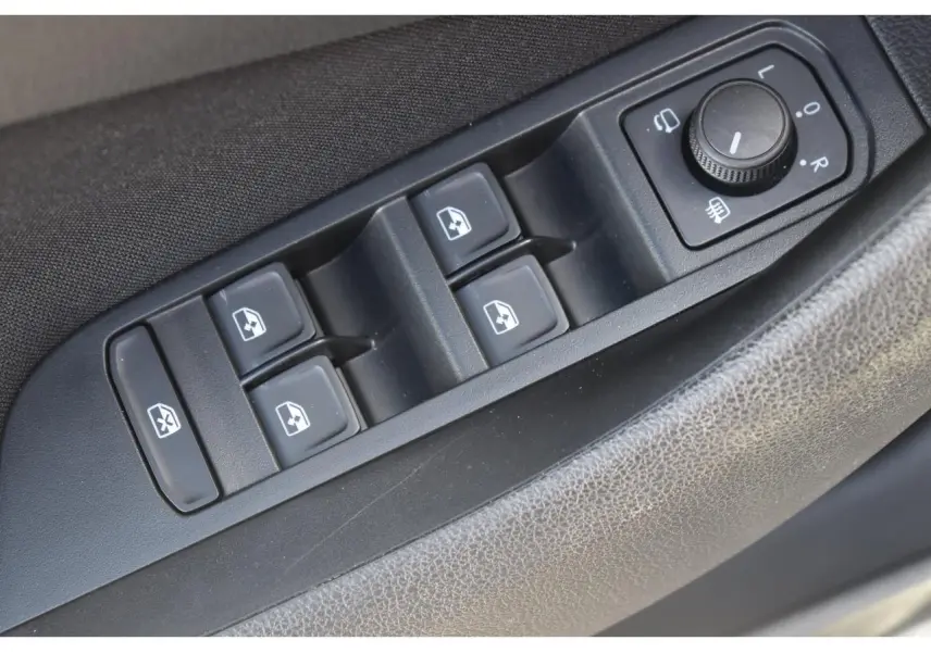 Gros plan sur les commandes de lève-vitres et réglage des rétroviseurs côté conducteur d'une Skoda Scala gris graphite.
