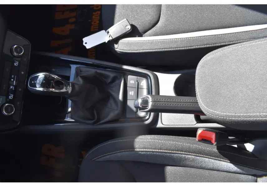 Vue plongeante sur la console centrale de la Skoda Scala gris graphite, avec levier de vitesse automatique et frein à main manuel.