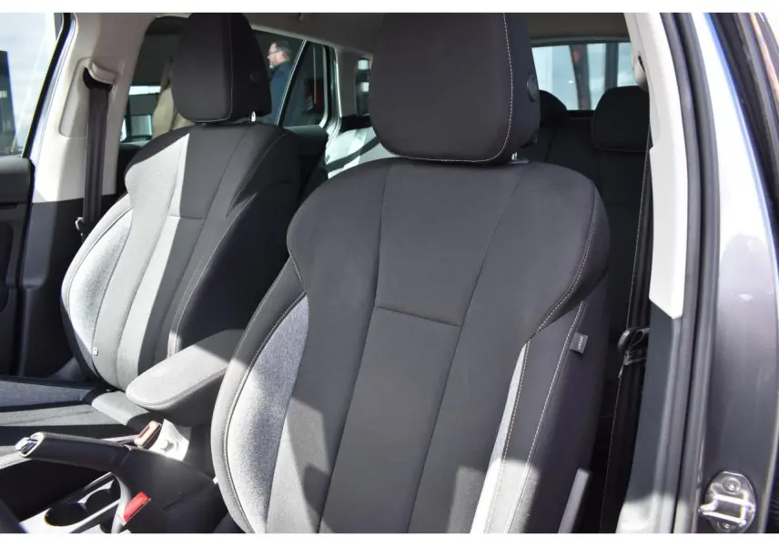 Vue rapprochée des sièges avant tissu gris et noir d’une Skoda Scala 2025, porte ouverte côté droit.