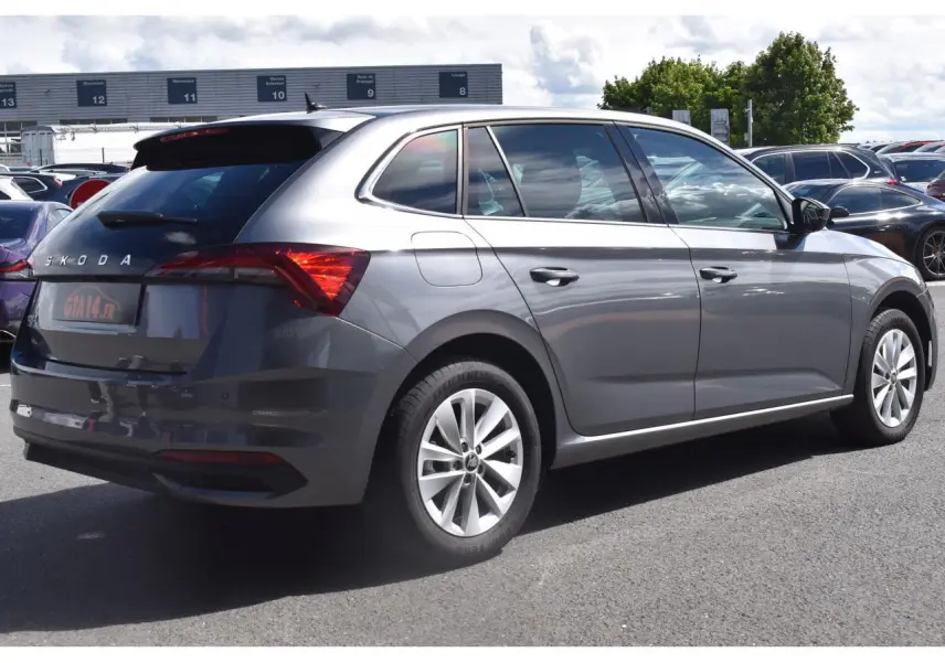 Vue 3/4 arrière droite d'une Skoda Scala gris graphite avec jantes alliage 16 pouces sur parking extérieur.