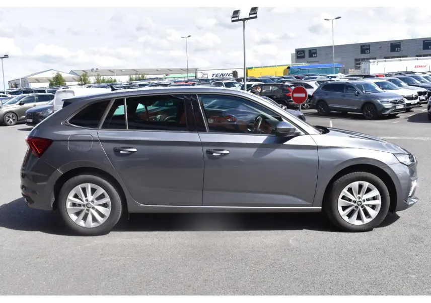 Vue de profil côté gauche d'une Skoda Scala gris graphite avec jantes alliage sur un parking extérieur.