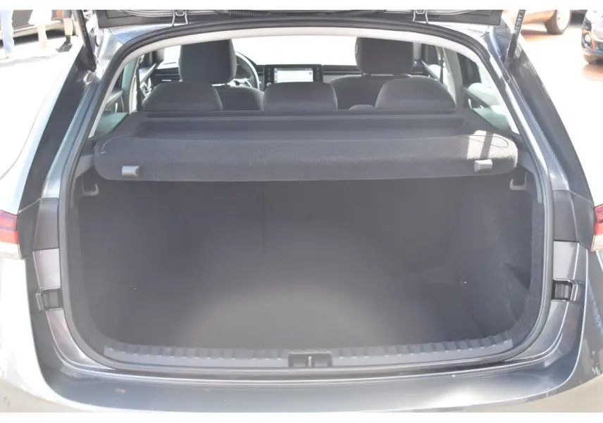 Coffre ouvert vu de l'arrière d'une Skoda Scala gris graphite, intérieur spacieux et banquette arrière visible.