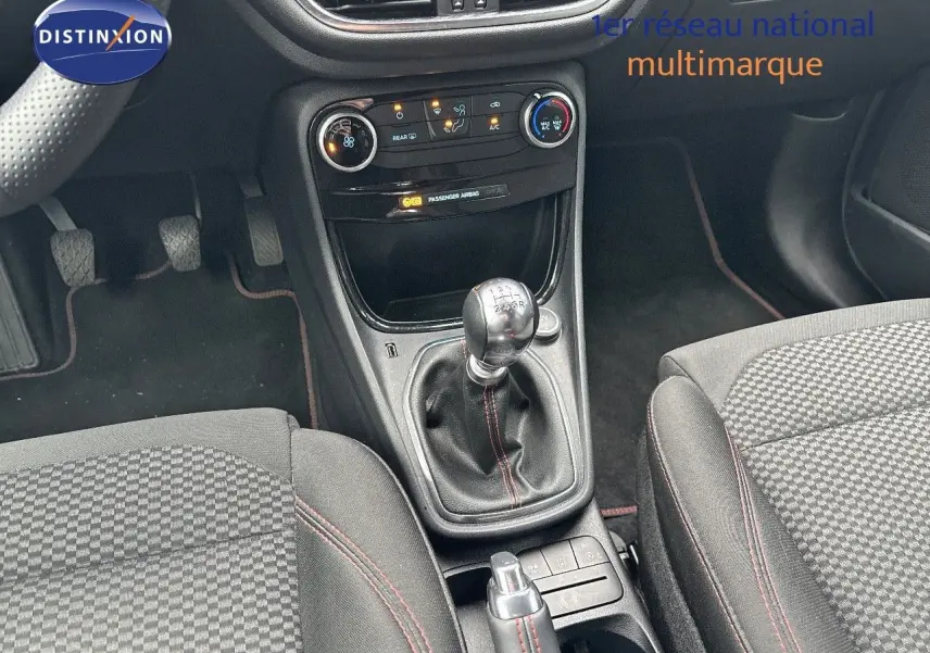 Intérieur du Ford Puma 2022 montrant la console centrale avec levier de vitesses manuel et sièges tissu noir à surpiqûres rouges.