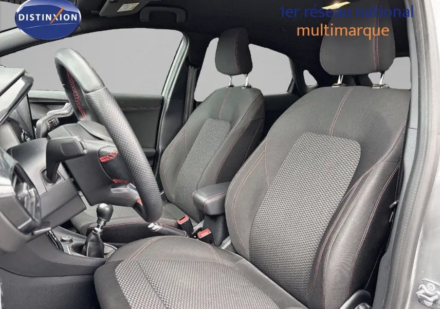 Intérieur avant du Ford Puma gris Solar, sièges noirs avec surpiqûres rouges et volant cuir perforé en vue latérale droite.