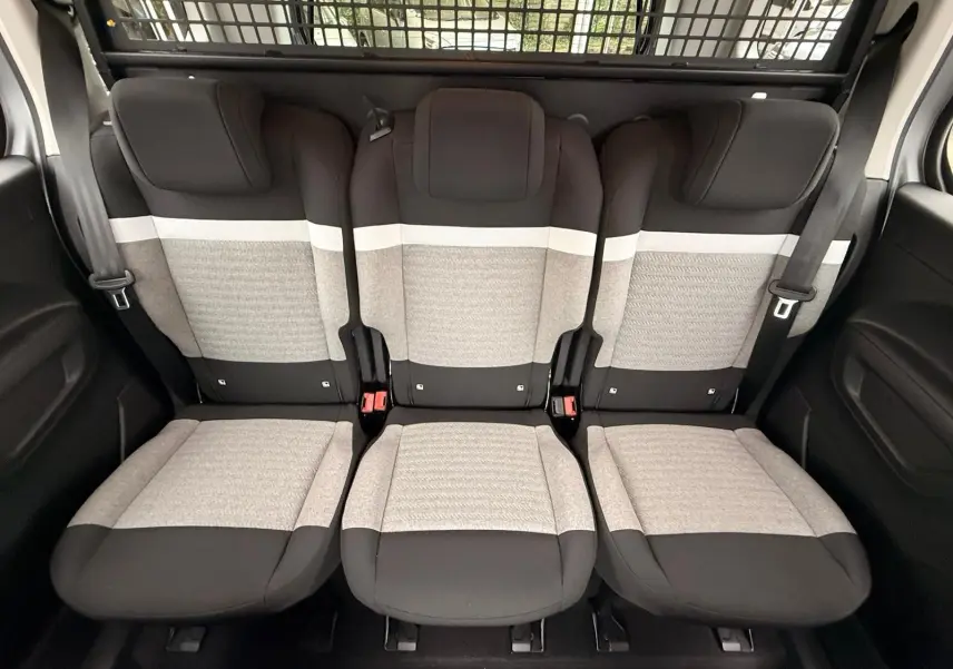 Vue intérieure des trois sièges arrière gris clair et noir du Citroën Berlingo Taille M 2025 avec ceinture de sécurité et grille de séparation.