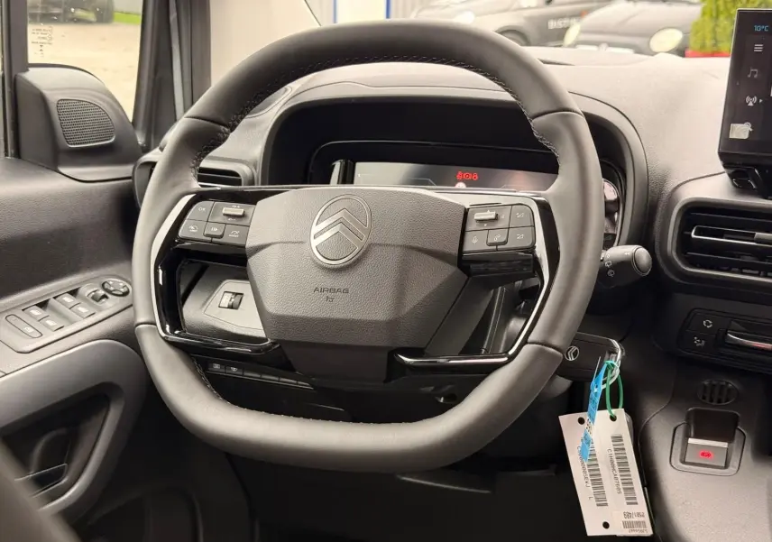Vue rapprochée du volant cuir noir de la Citroën Berlingo 2025 avec commandes intégrées et tableau de bord numérique.