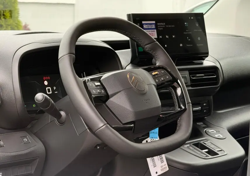 Vue intérieure centrée sur le volant cuir et le tableau de bord numérique du Citroën Berlingo 2025 gris Artense.