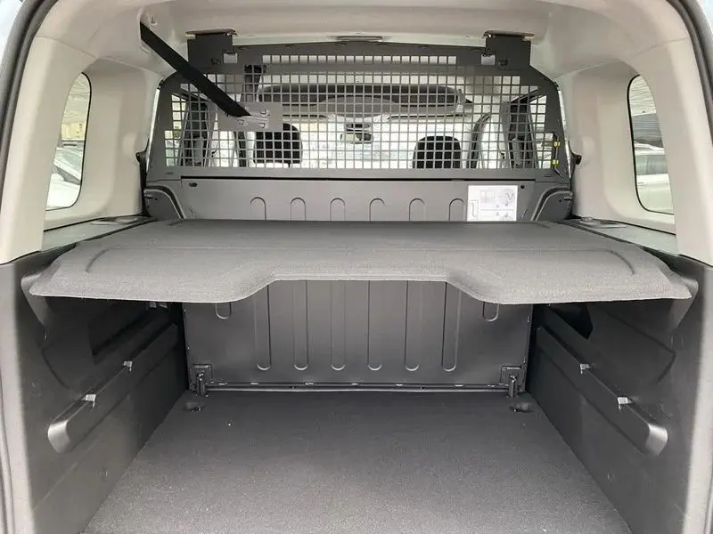 Vue intérieure arrière du Citroën Berlingo gris Artense, montrant le coffre avec séparation grillagée et tablette de rangement.