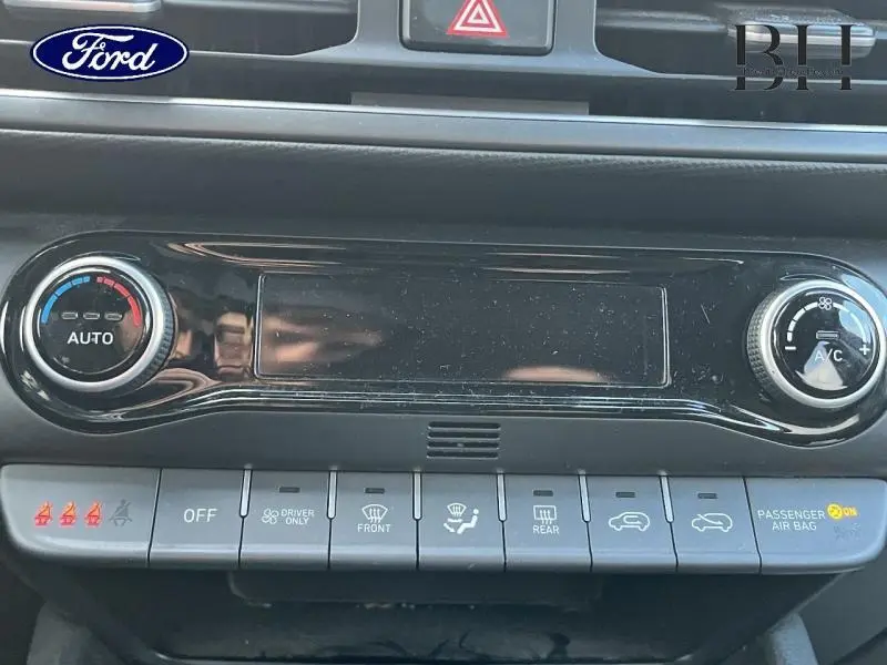 Tableau de bord avec commandes de climatisation et boutons fonctionnels, vue rapprochée intérieure.