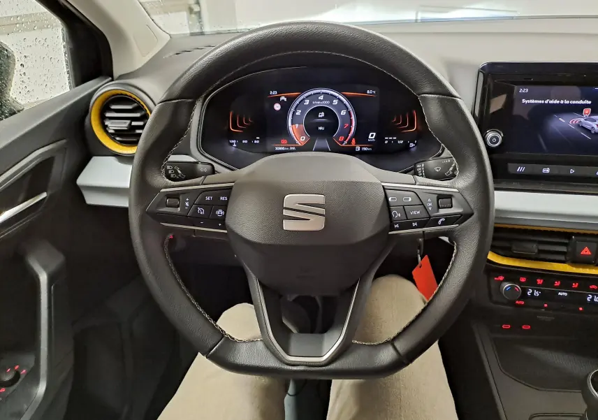 Vue intérieure centrée sur le volant de la SEAT Ibiza 2024, avec tableau de bord numérique et touches multifonctions.
