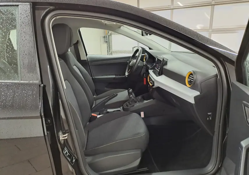 Vue intérieure côté conducteur de la SEAT Ibiza noir minuit 2024, avec tableau de bord moderne et sièges tissu gris.