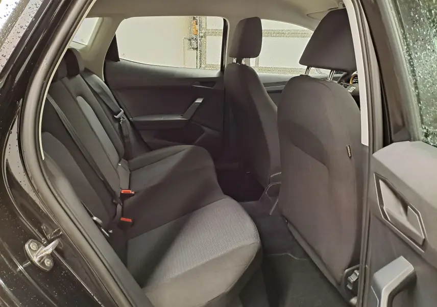 Vue intérieure arrière de la SEAT Ibiza noir minuit 2024, montrant les sièges arrière et la porte ouverte côté gauche.