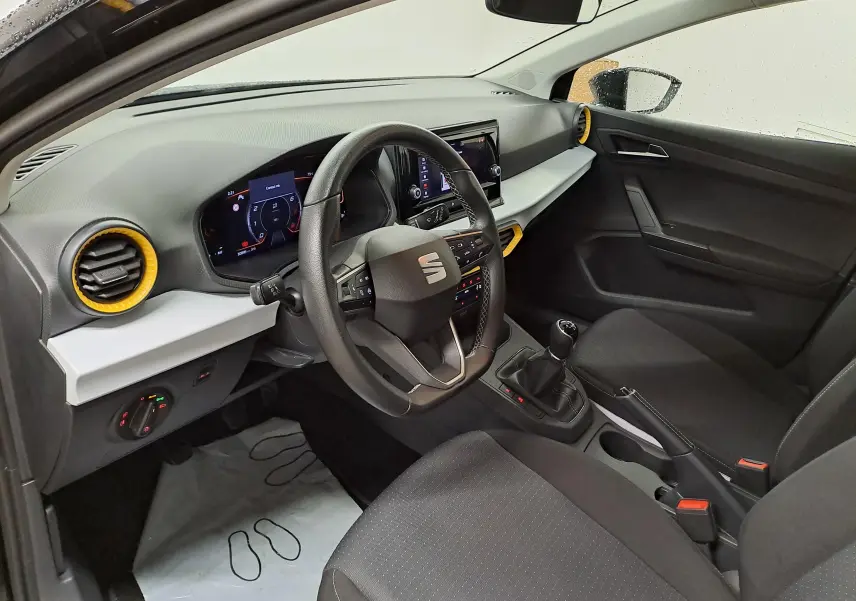 Vue intérieure côté conducteur de la SEAT Ibiza 2024, tableau de bord noir avec touches jaunes autour des aérateurs.