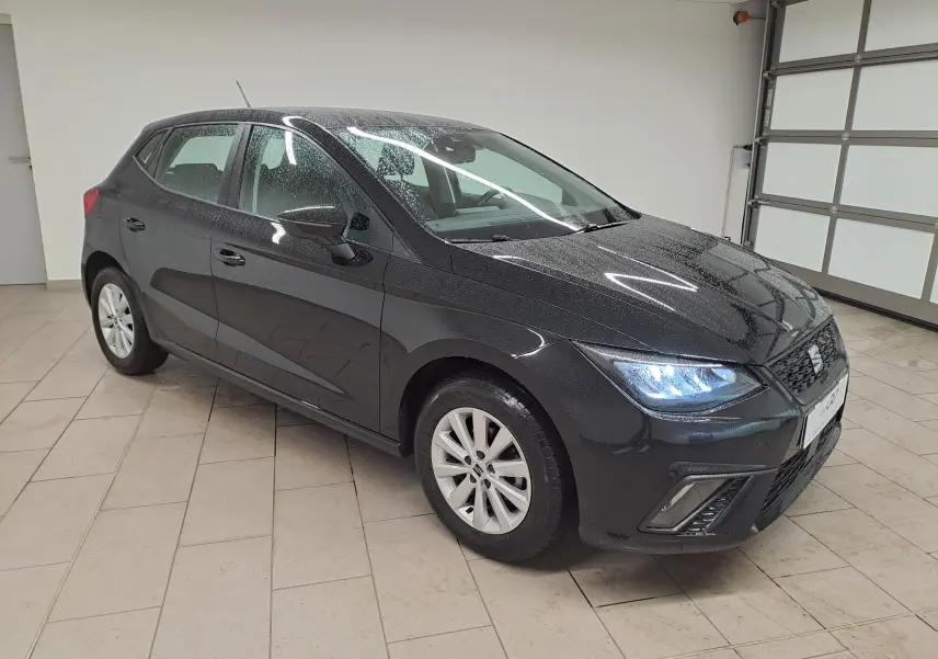 SEAT Ibiza 2024 noir minuit vue 3/4 avant droit avec projecteurs EcoLED allumés et jantes alliage 15 pouces.