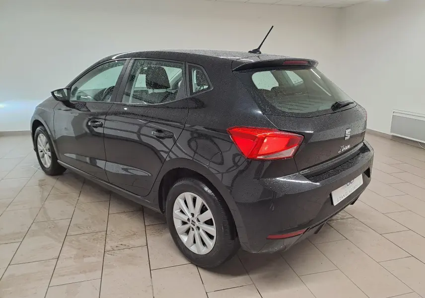 Vue 3/4 arrière droite d'une SEAT Ibiza noire minuit 2024 avec jantes alliage 15'' et feux arrière LED allumés.