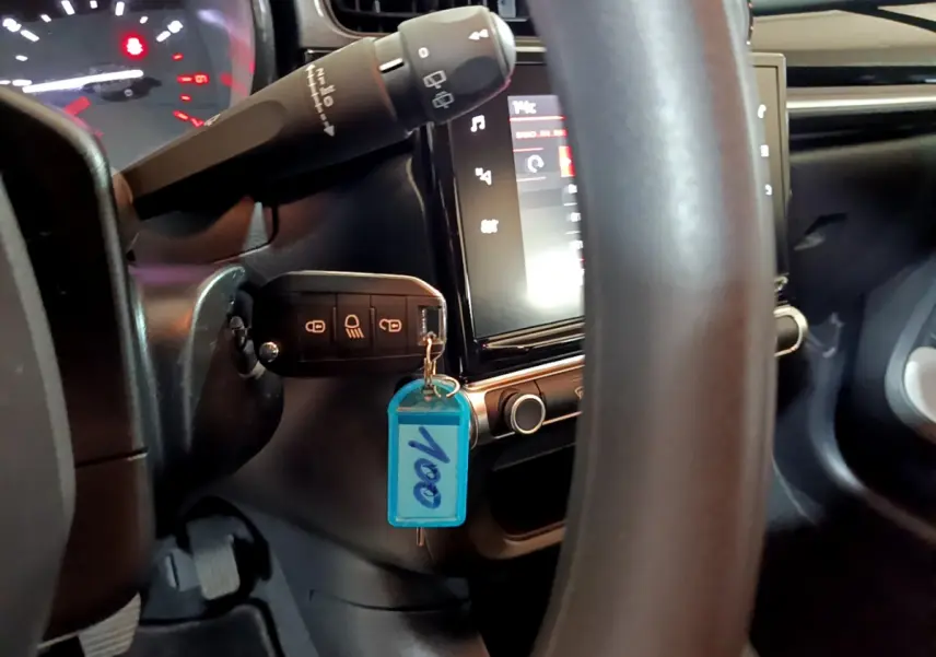 Vue rapprochée du tableau de bord et du volant de la Citroën C3 beige avec clé insérée et écran tactile allumé.