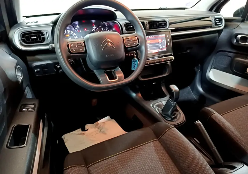 Vue intérieure avant de la Citroën C3 beige 2022, volant multifonctions, écran tactile et boîte manuelle visible.