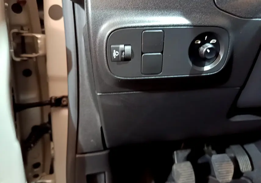 Vue rapprochée des commandes noires côté gauche sous le tableau de bord beige de la Citroën C3 2022.