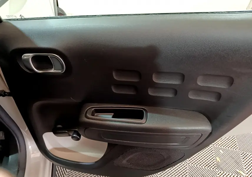 Gros plan sur la porte intérieure côté conducteur de la Citroën C3 beige, avec poignée et haut-parleur intégrés.