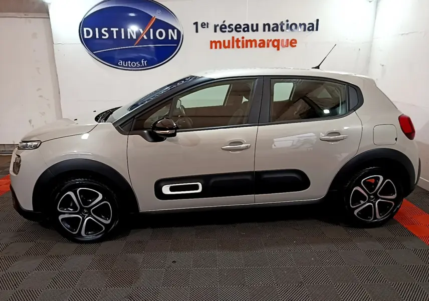 Profil côté gauche d'une Citroën C3 beige 2022 avec protections latérales noires et jantes distinctives en alliage.