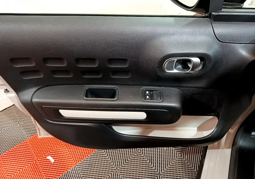 Gros plan sur la porte avant gauche beige de la Citroën C3 2022, avec poignée intérieure noire et blanche.