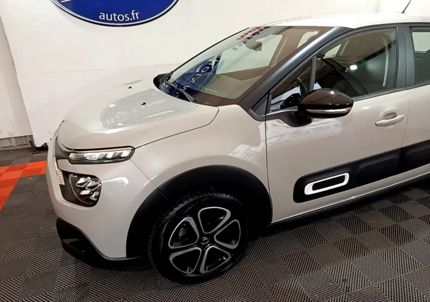 Vue 3/4 avant gauche d'une Citroën C3 beige avec protections latérales noires et jantes stylisées.