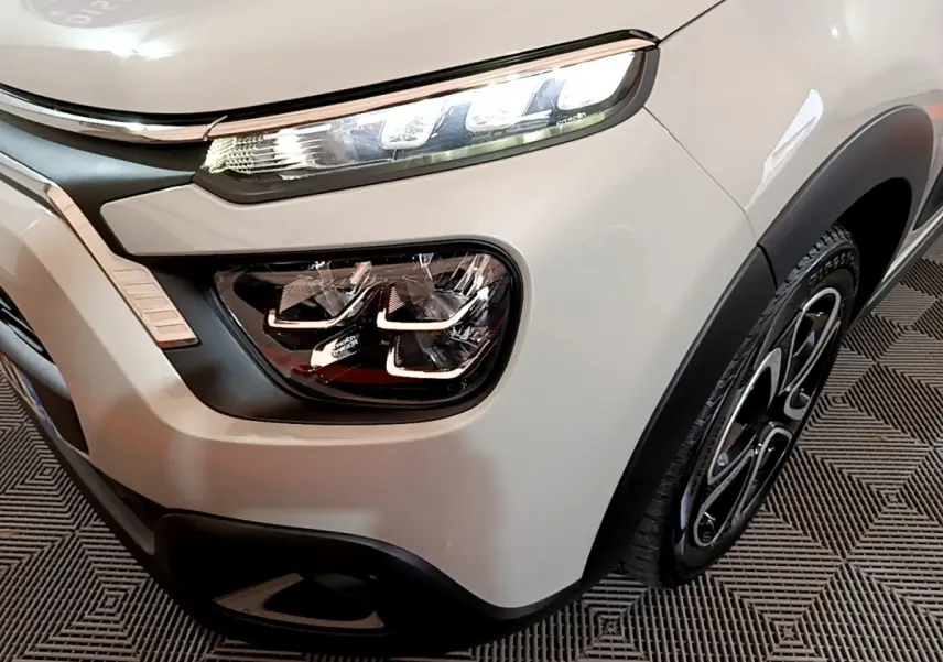 Gros plan sur l'avant droit beige de la Citroën C3 2022 avec phares LED et jante noire stylisée.
