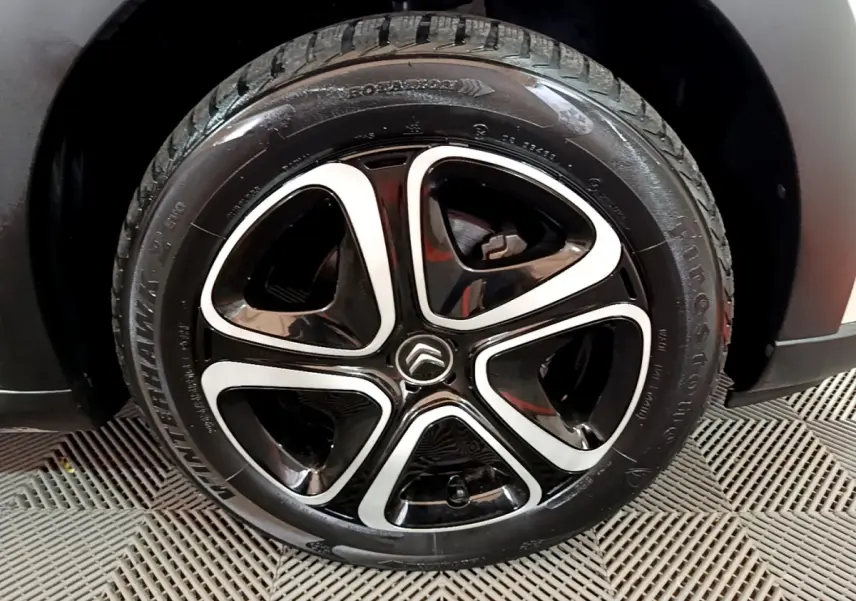 Gros plan sur la roue avant droite d'une Citroën C3 beige, montrant le pneu Firestone et l'aile noire.