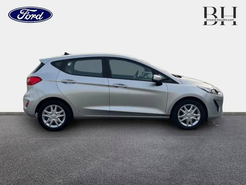 Vue de profil côté gauche d'une Ford Fiesta 2020 gris lunaire avec enjoliveurs et poignées ton carrosserie.