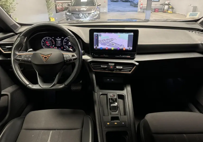 Vue intérieure frontale du tableau de bord du CUPRA Formentor gris, avec écran tactile central et volant sport multifonction.