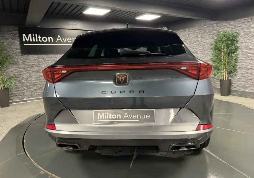 Vue arrière d'une CUPRA Formentor gris magnétique avec bandeau LED Infinite Light et double sortie d'échappement noire.