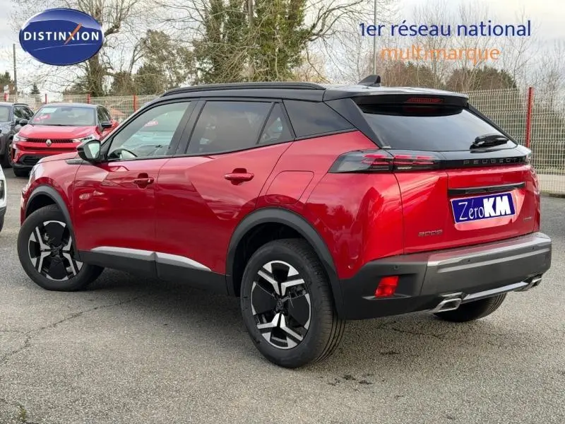 Vue 3/4 arrière droite d'un Peugeot 2008 rouge avec toit noir et jantes alliage noires et argentées.