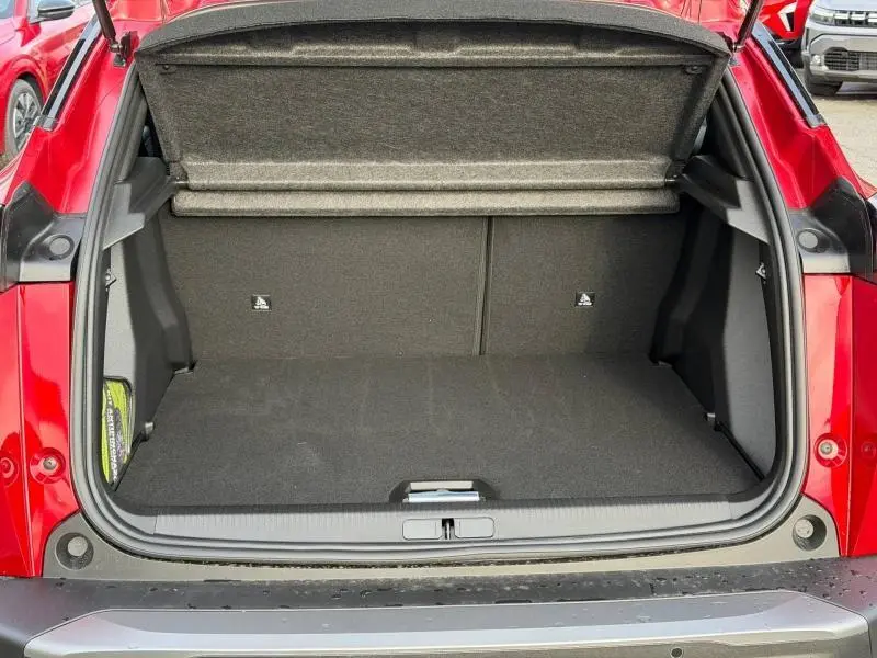 Coffre ouvert vu de l'arrière d'un Peugeot 2008 rouge, montrant l'espace de chargement vide et la tablette cache-bagages.