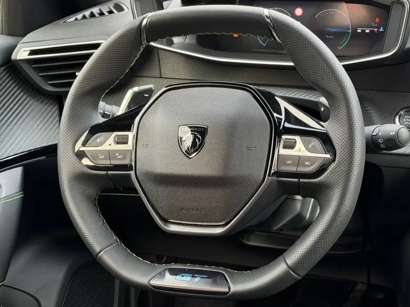 Vue rapprochée du volant cuir noir perforé avec logo Peugeot et badge GT du Peugeot 2008 Hybrid 145ch 2025.