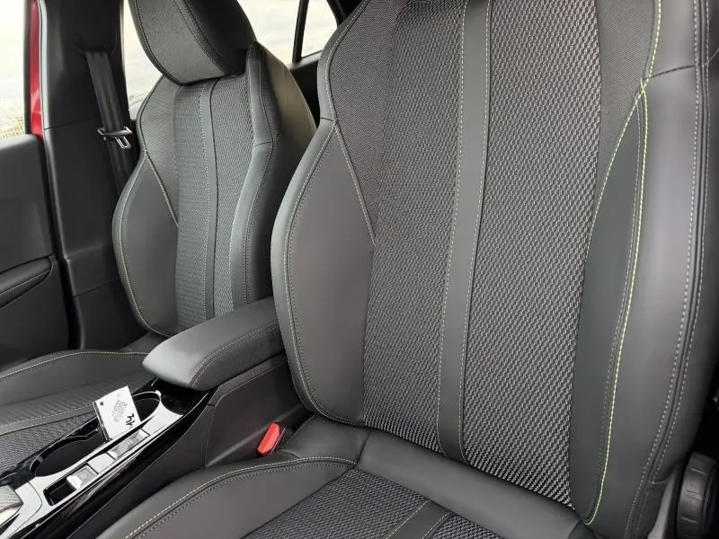 Gros plan sur les sièges avant en tissu et cuir noir avec surpiqûres vertes du Peugeot 2008 1.2 Hybrid 145ch GT 2025.