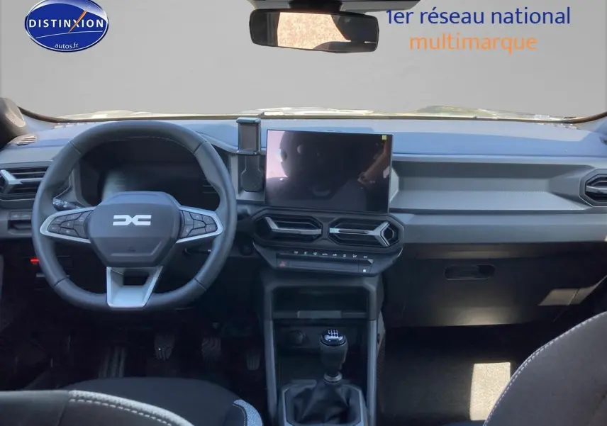 Vue intérieure avant du tableau de bord et volant du Dacia Duster 2026 avec écran tactile et boîte manuelle.