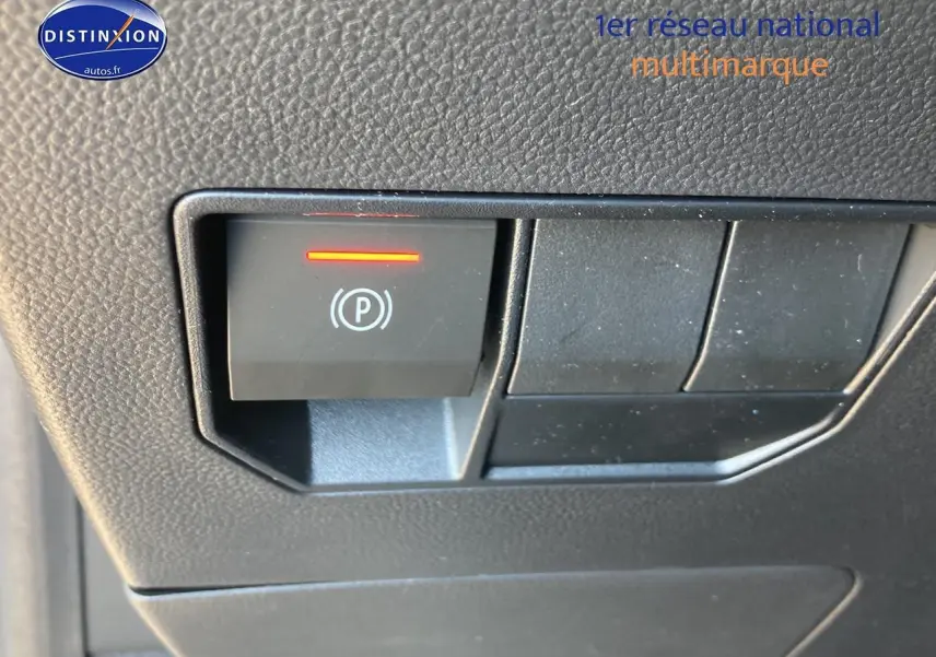 Gros plan sur le bouton de frein de stationnement électrique allumé dans l'habitacle du Dacia Duster gris schiste.