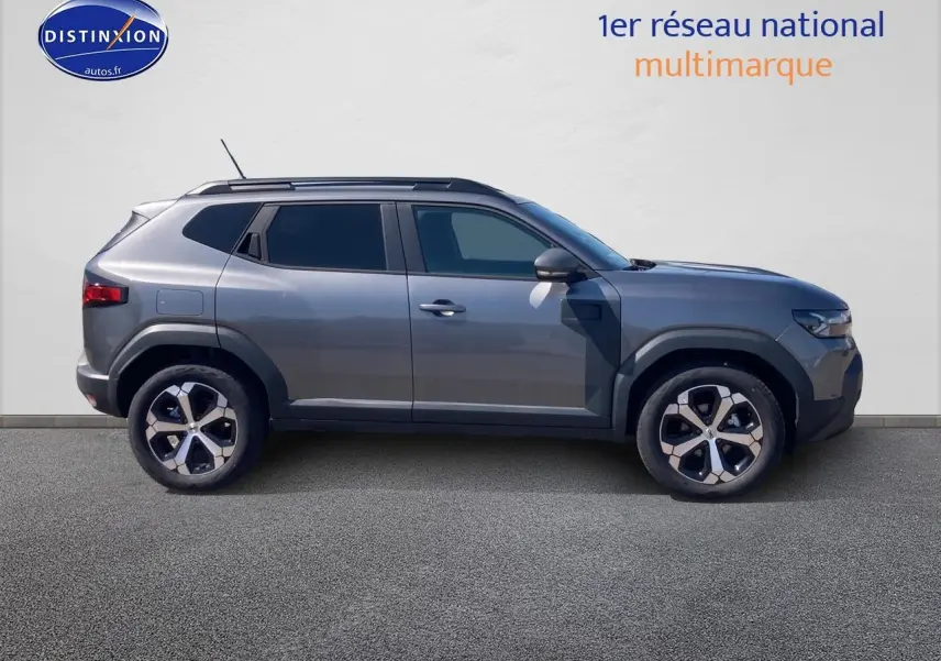 Vue latérale droite du Dacia Duster 2026 gris schiste avec jantes alliage et vitres arrière surteintées.