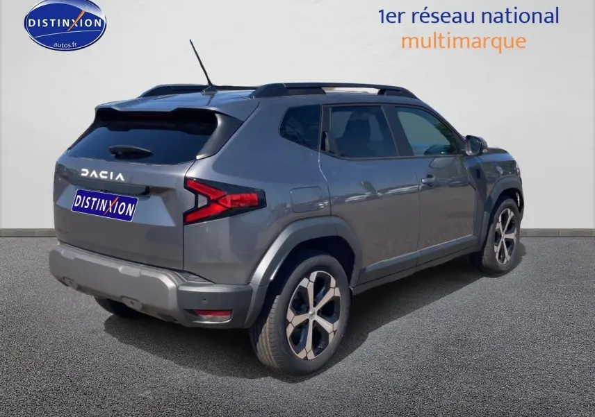 Vue 3/4 arrière droite du Dacia Duster gris schiste avec barres de toit et jantes alu distinctives.
