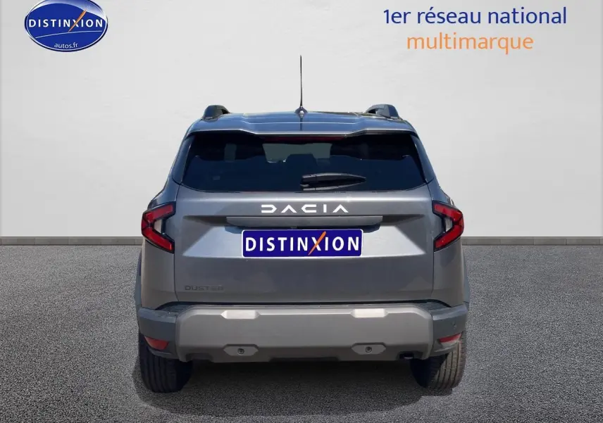 Vue arrière du Dacia Duster gris schiste 2026 avec feux LED et barres de toit visibles.