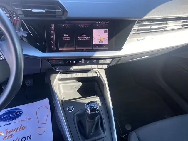 Vue intérieure centrée sur la console centrale et le levier de vitesses manuel de l'Audi A3 30 TDI Business Line 2021 en gris foncé.