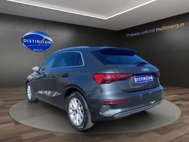 Vue 3/4 arrière gauche d'une Audi A3 30 TDI Business Line gris foncé, avec feux LED et jantes argentées visibles.