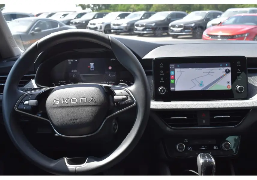 Vue intérieure centrée sur le volant noir Skoda et l'écran tactile 8,25'' affichant la navigation.