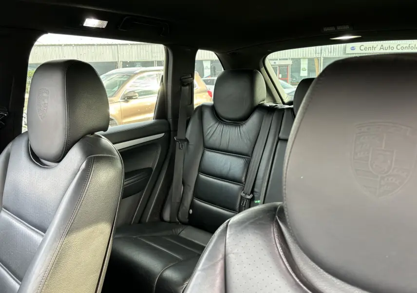 Intérieur noir cuir du Porsche Cayenne S 4,8L V8 2007, vue rapprochée des sièges avant et arrière avec appuie-têtes embossés.