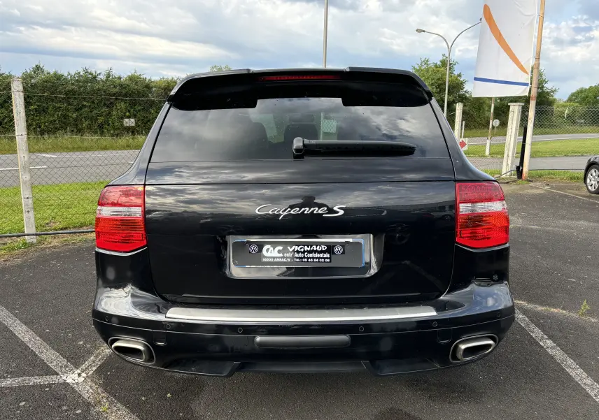Vue arrière d'un Porsche Cayenne S noir de 2007 avec double sortie d'échappement et feux arrière rouges.