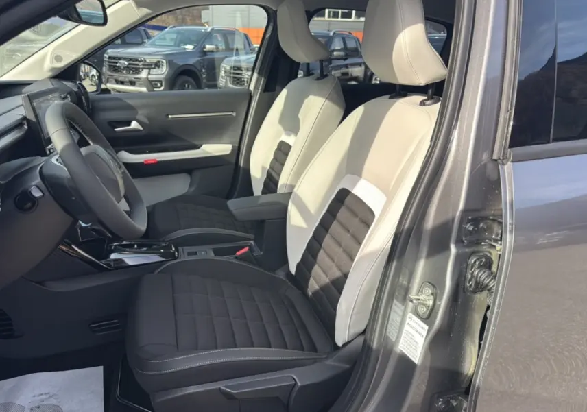 Vue intérieure côté gauche du Citroën C3 Aircross gris mercury avec sièges tissu bicolores et accoudoir central.