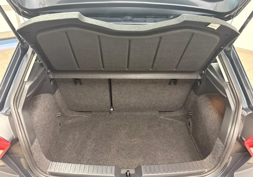 Coffre ouvert de la SEAT Ibiza 2024 gris magnétique, vue arrière montrant l’espace de rangement vide et la moquette intérieure.